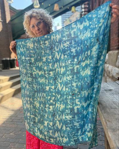Person holding a large blue patterned fabric outdoors.