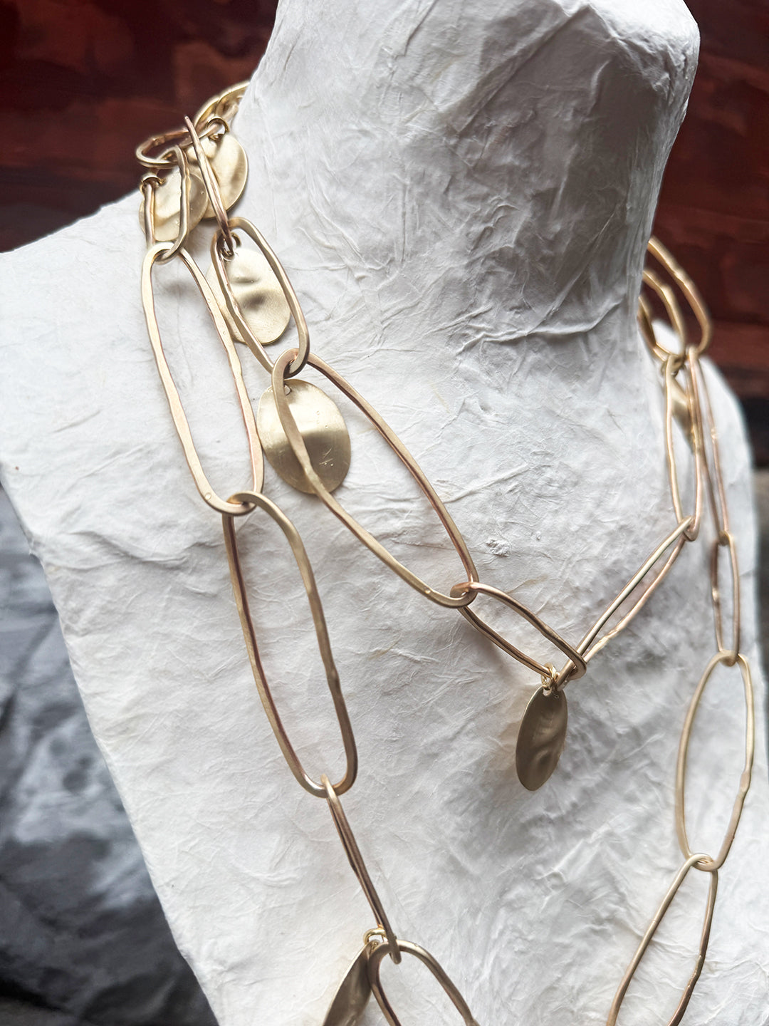 Gold chain necklace on a mannequin bust against a neutral background