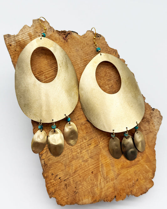 Gold earrings with dangling components on a wooden block