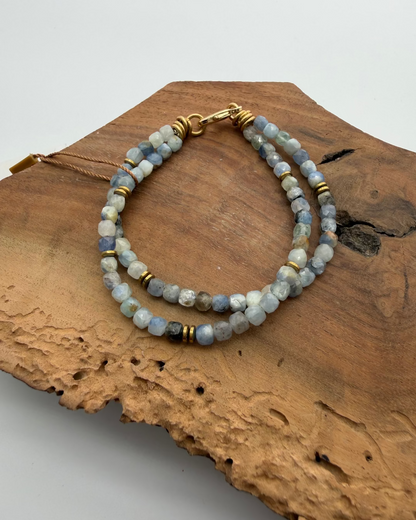 Two beaded bracelets on a piece of wood with a white background