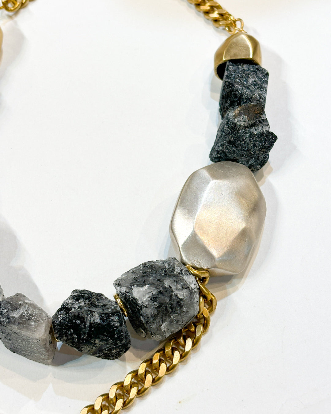 Necklace with gold chain, gray beads, and a large silver bead on a white background