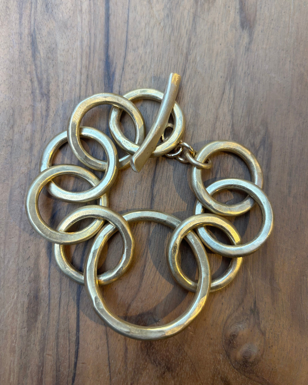 Gold circular link bracelet on a wooden surface