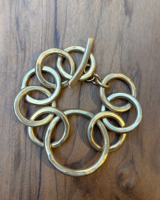 Gold circular link bracelet on a wooden surface