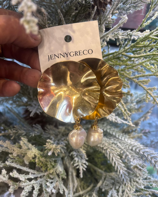 Textured disk earrings with a pearl drop held by a hand against a christmas tree.