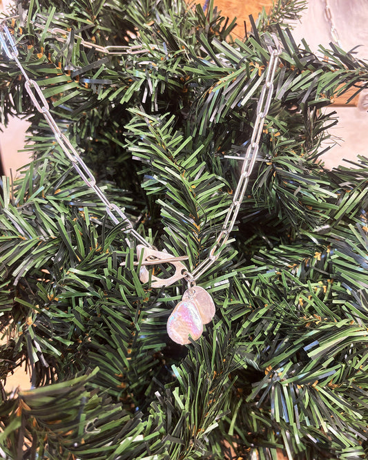 Necklace with a pearl pendant on a green leafy background