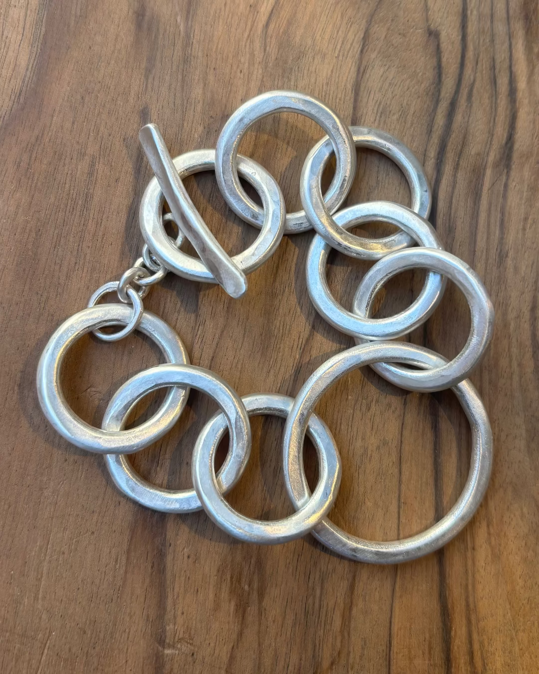 Silver circular link bracelet on a wooden surface
