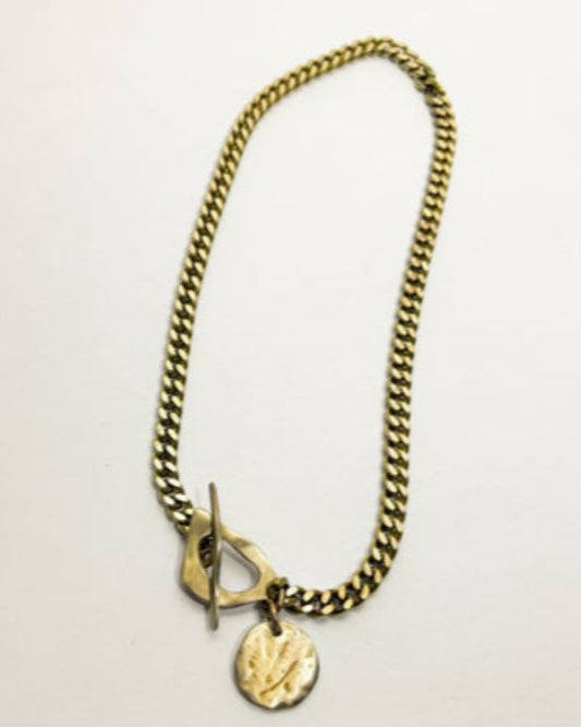 Gold chain necklace with a round pendant on a light gray background