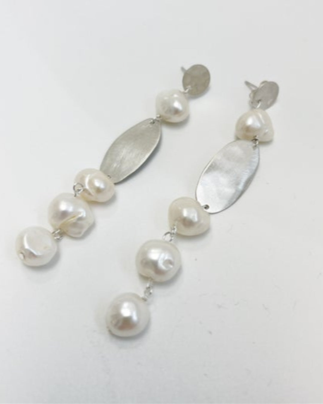 Pearl and silver drop earrings on a white background