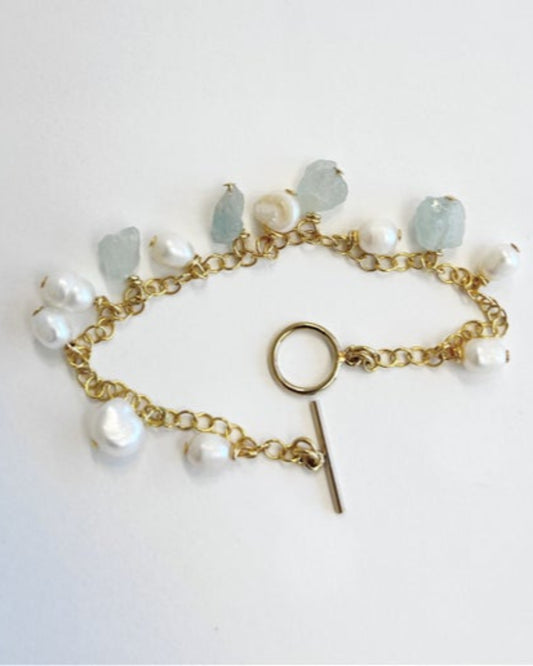 Gold bracelet with pearls and gemstones on a white background