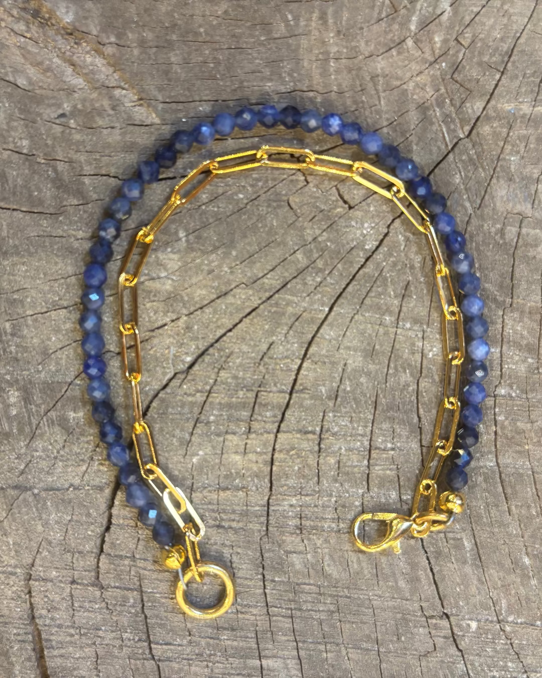 Bracelet with blue beads and gold chain on a wooden surface