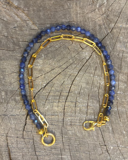 Bracelet with blue beads and gold chain on a wooden surface