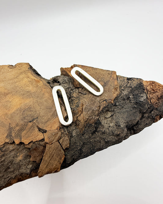 Two white metal loops on a piece of brown wood against a white background