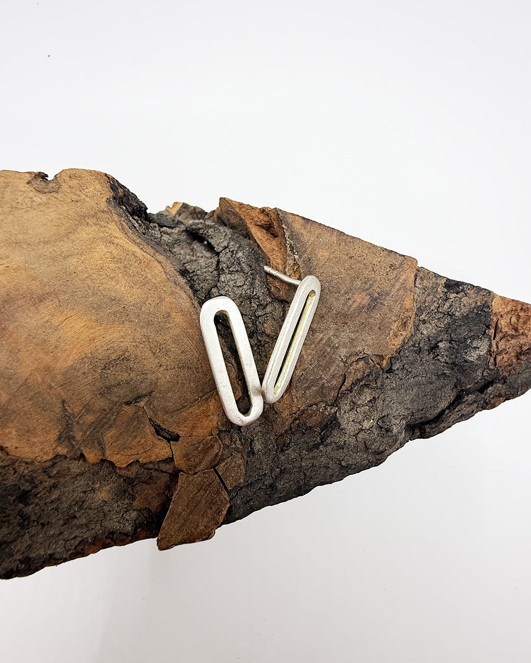 Silver paperclip on a piece of wood with a white background