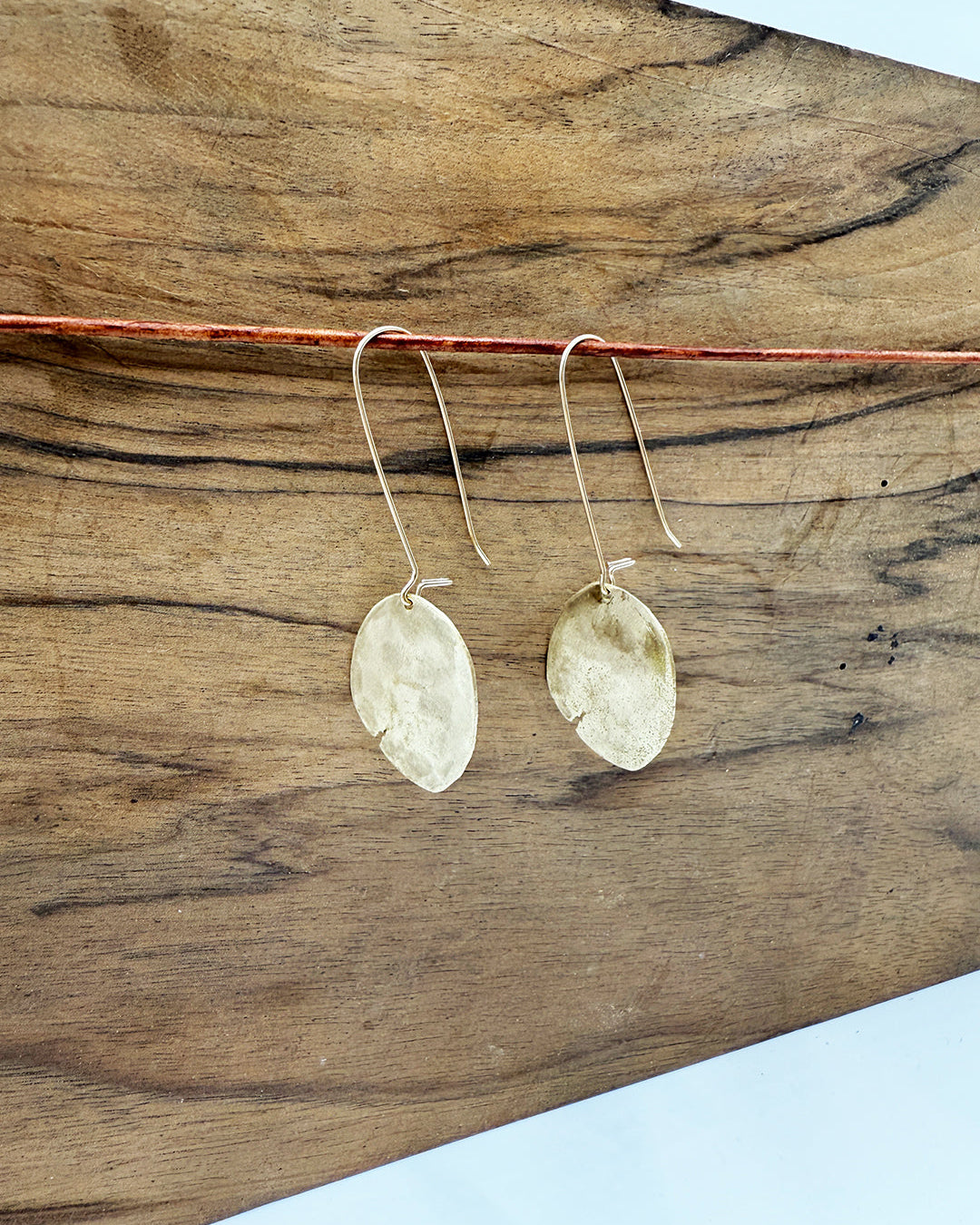 Gold earrings on a wooden surface