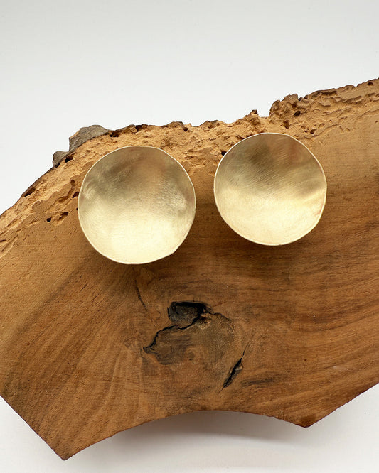 Gold earrings on a wooden surface