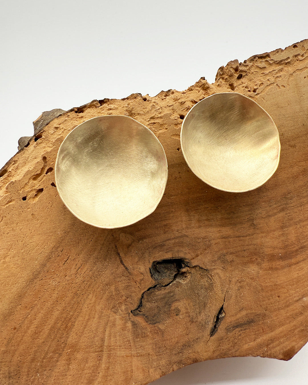 Pair of gold earrings on a wooden surface