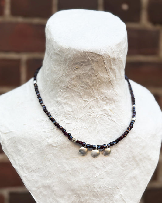 Necklace with beads on a mannequin bust against a brick wall background
