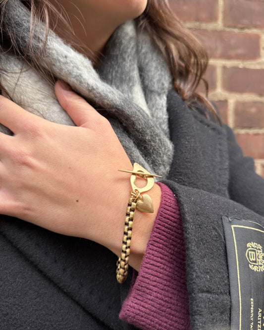 Close-up of a person's hand wearing gold bracelets with a blurred background
