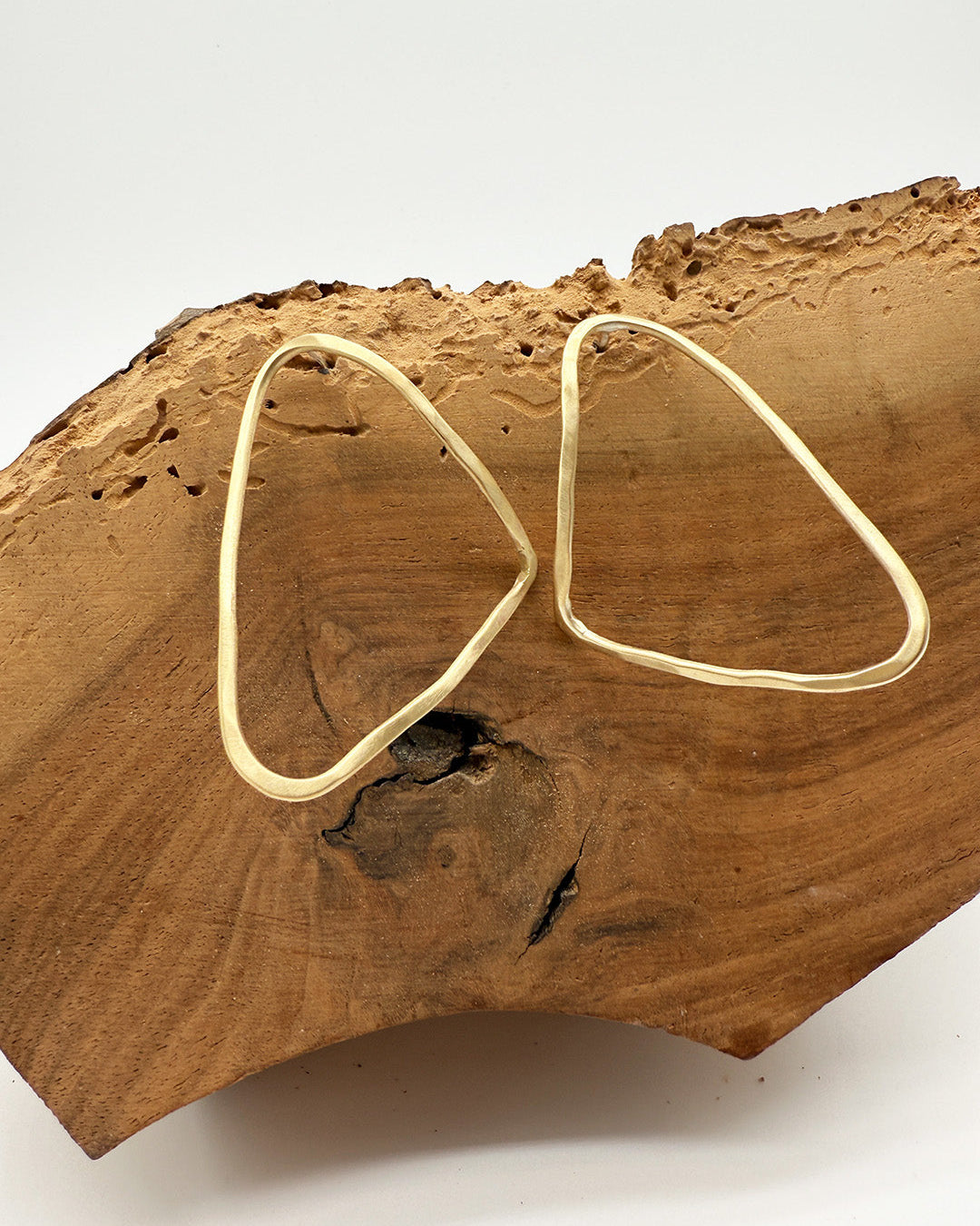 Gold hoop earrings on a wooden surface