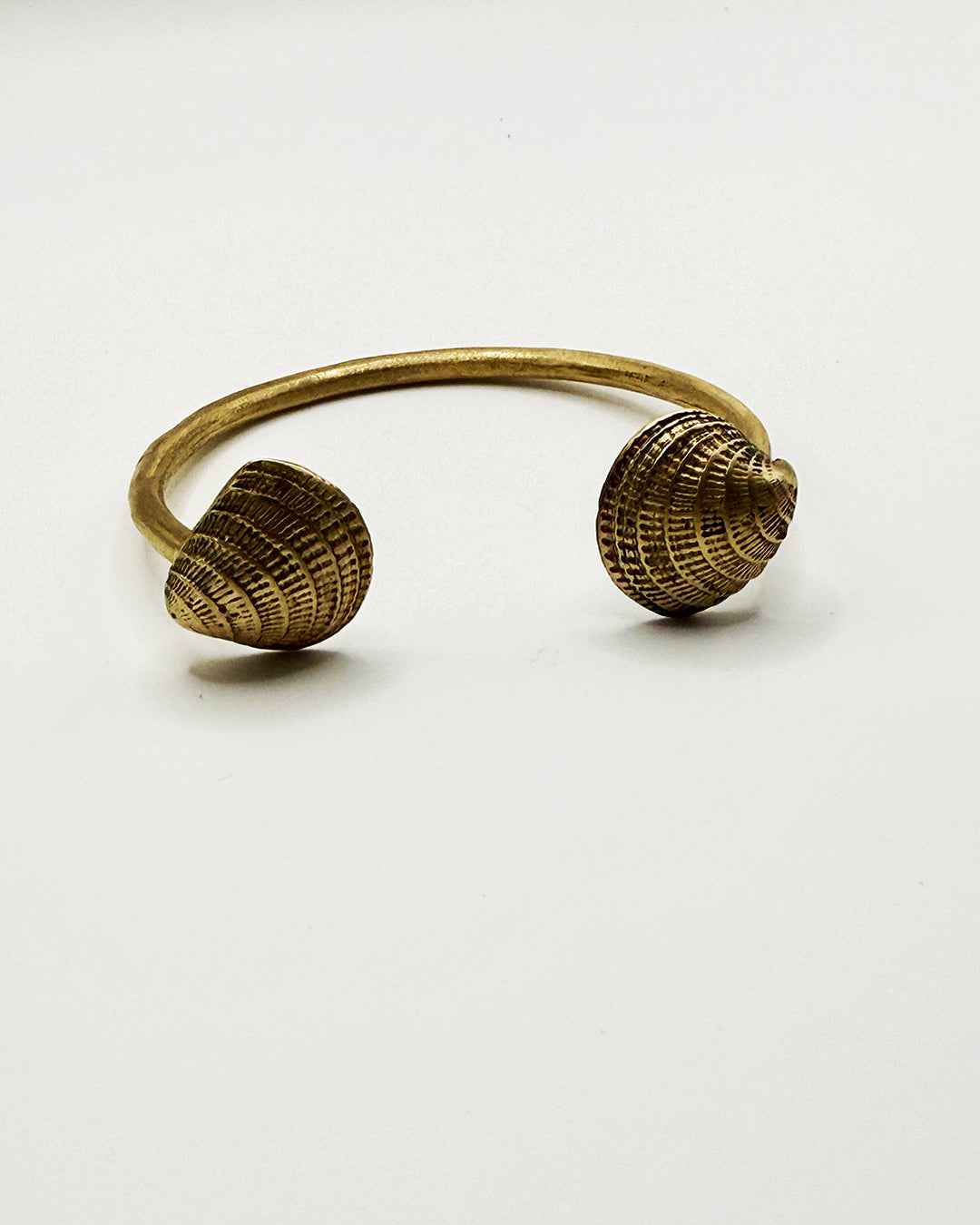 Brass shell-shaped bracelet on a white background
