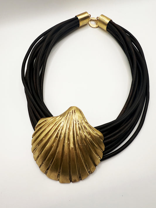 Necklace with black cord and gold shell pendant on a white background