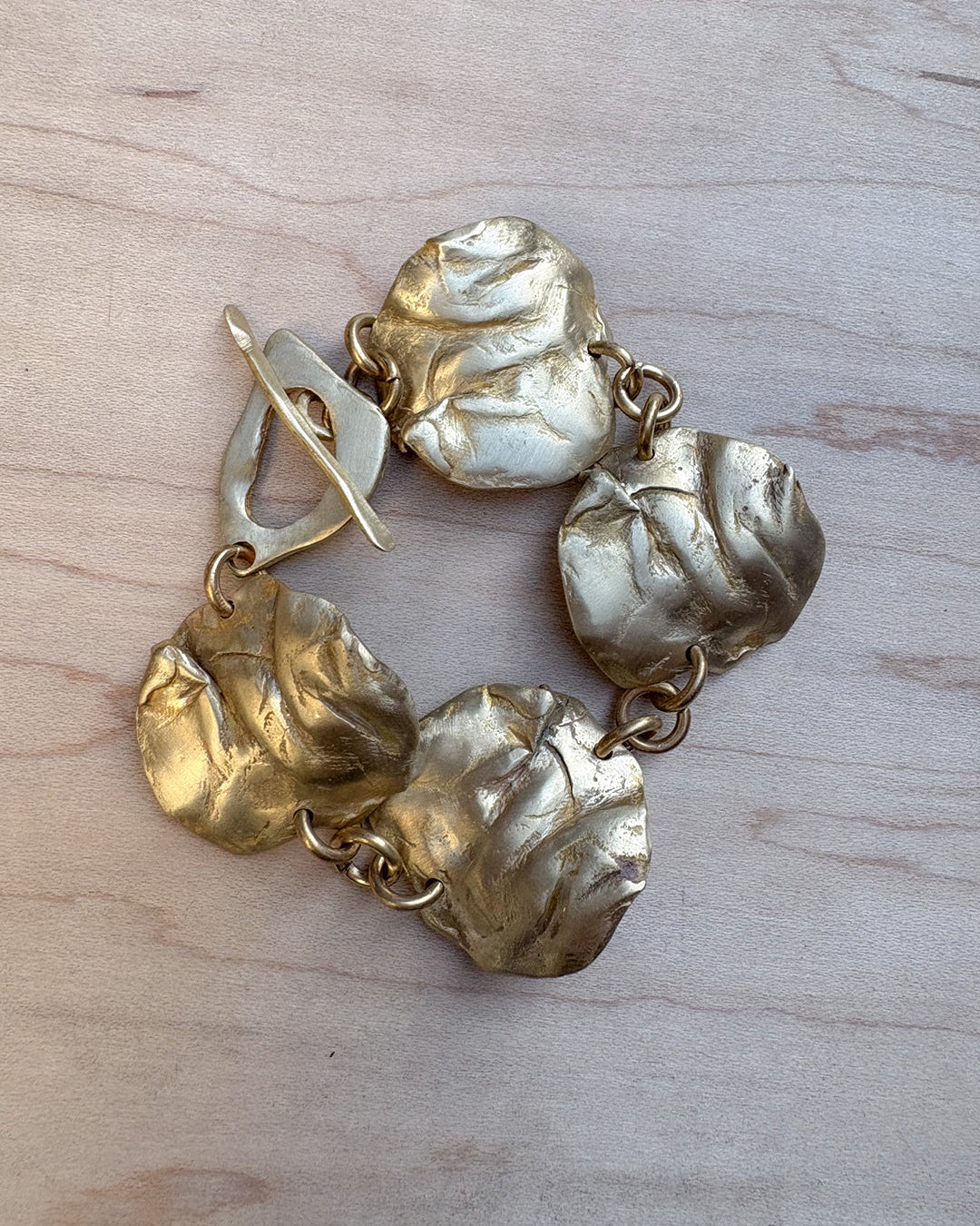 Bronze textured bracelet on a light wood surface