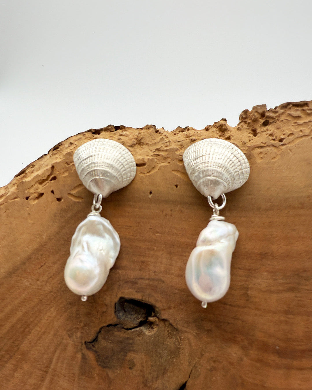 Pair of shell and pearl earrings on a wooden surface