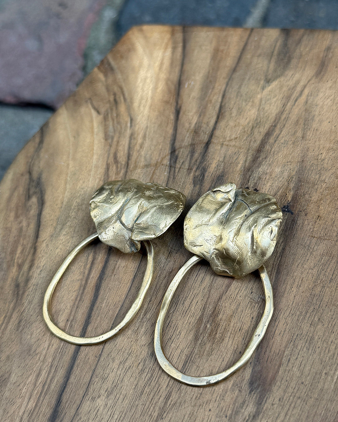Pair of gold hoop earrings with coral detail on a wooden surface