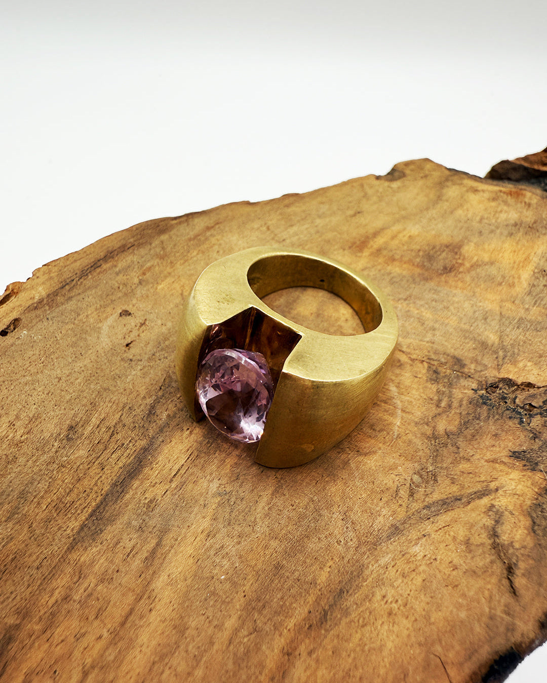 Gold ring with a pink gemstone on a wooden surface