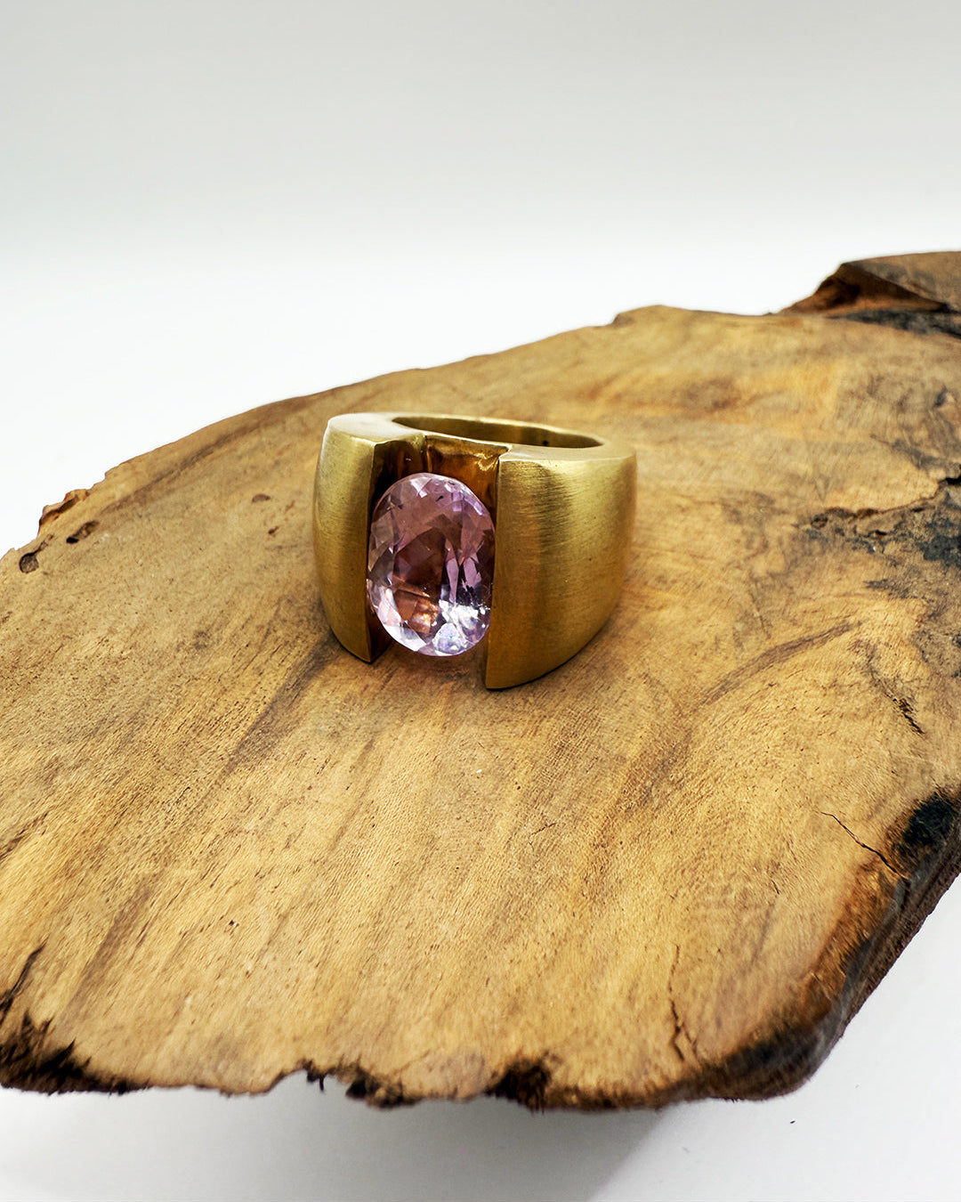 Gold ring with a pink gemstone on a wooden surface