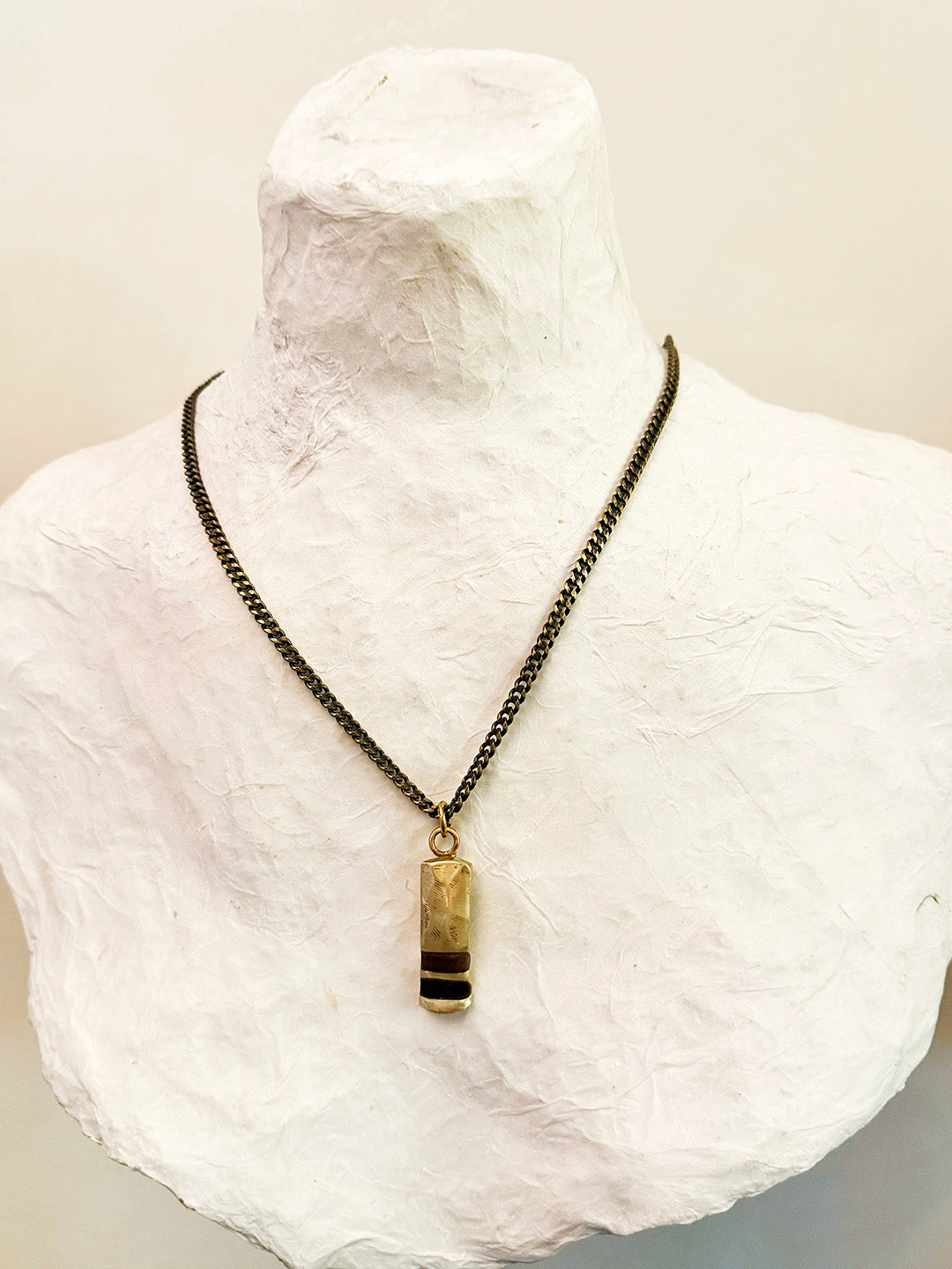 Necklace with a pendant on a mannequin bust against a neutral background