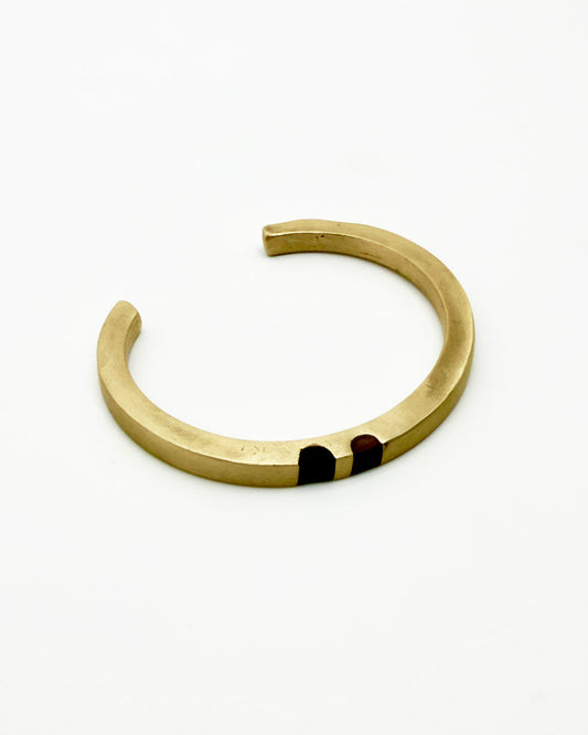 Gold bracelet with a dark red stone on a white background