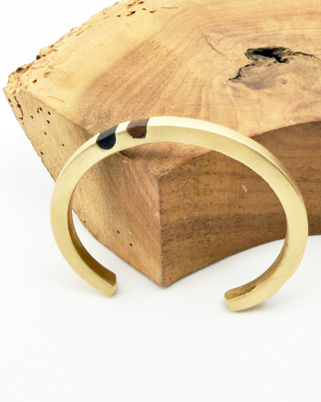 Gold bracelet on a wooden block with a white background