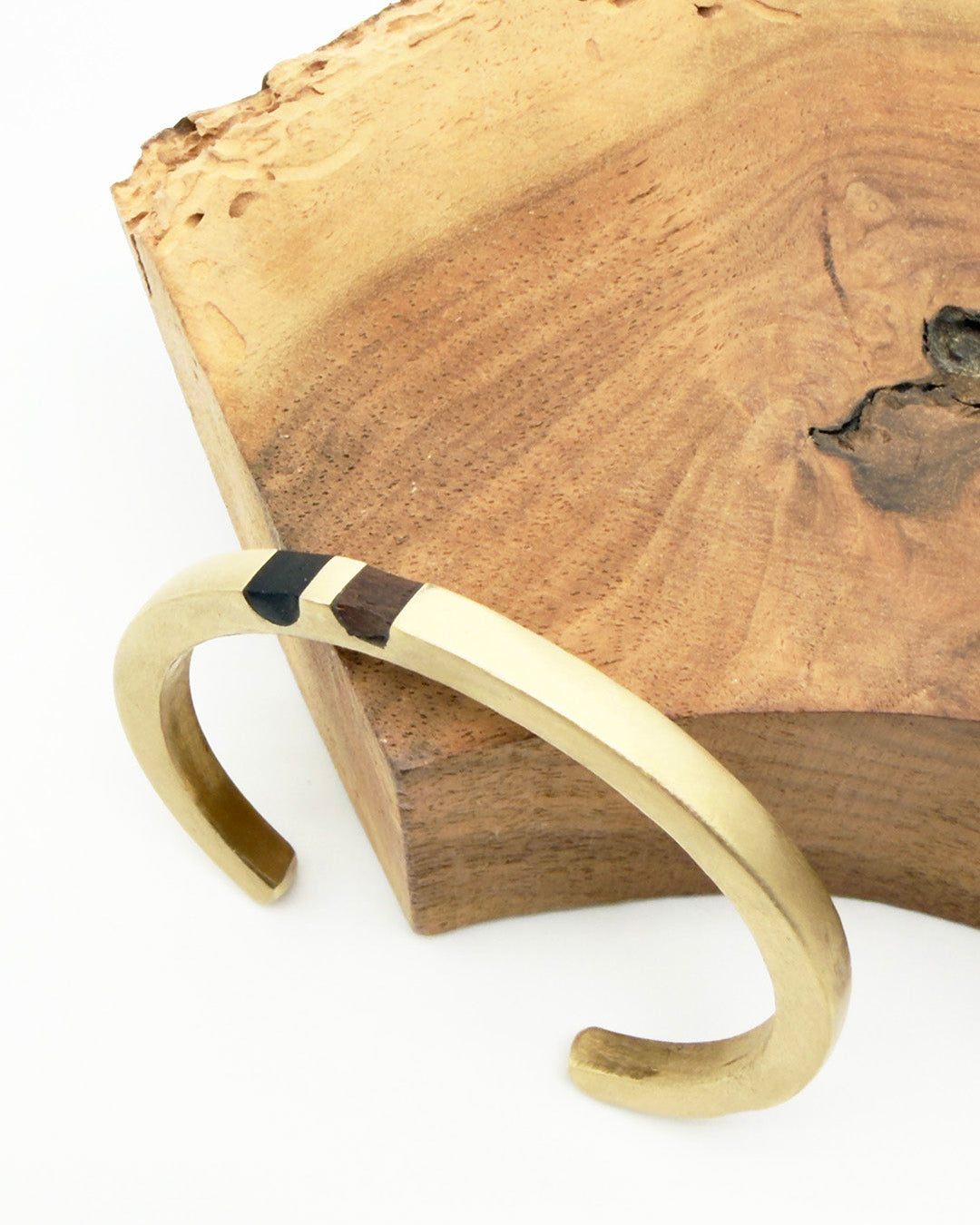 Gold bracelet with black accent on a wooden surface