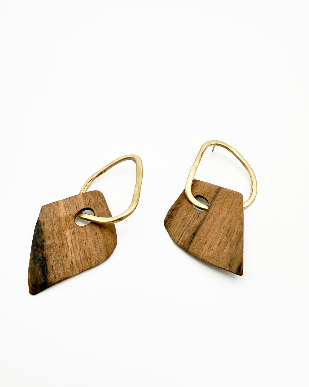 Pair of earrings with wooden and gold components on a white background