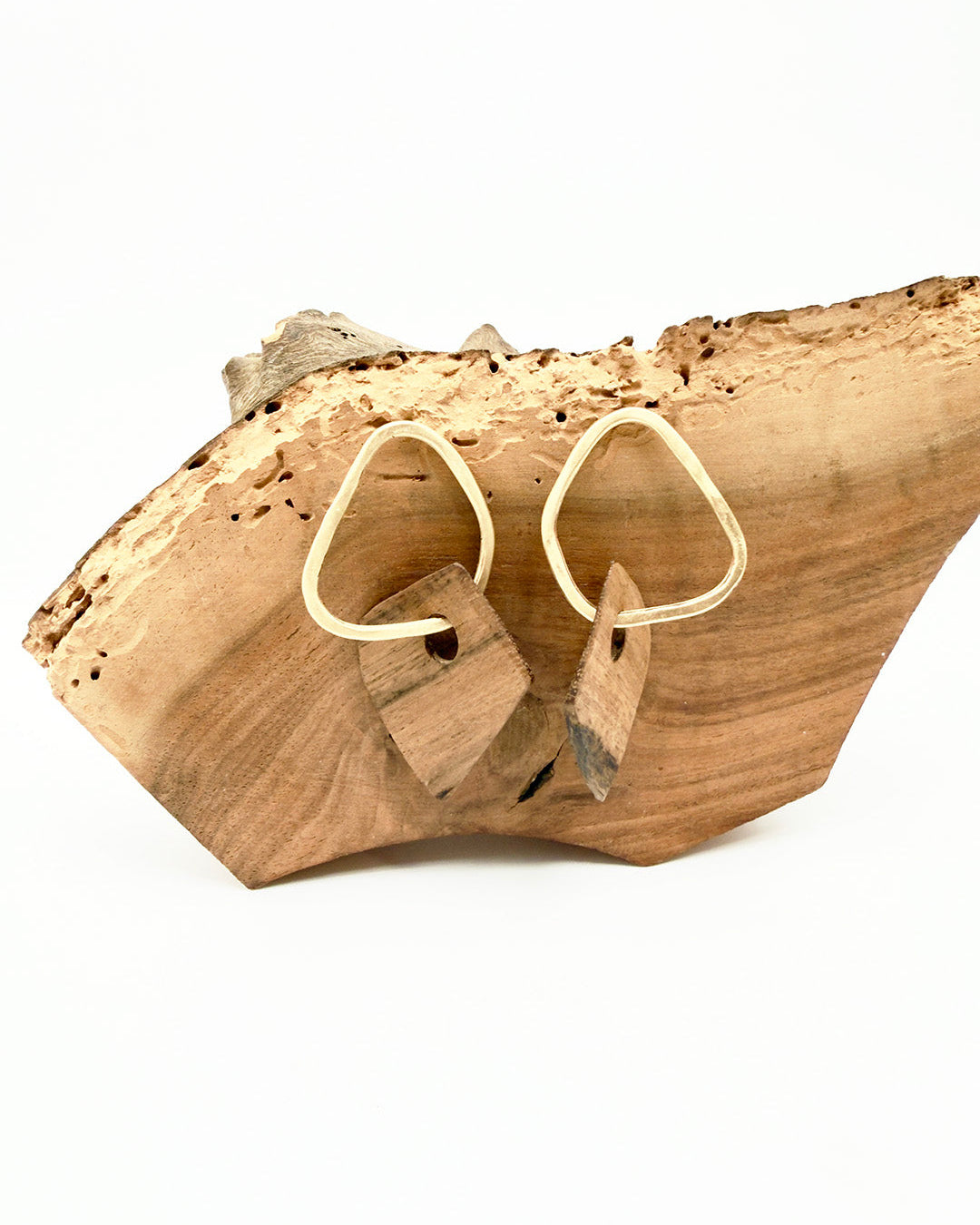 Wooden earrings on a natural wooden block with a white background