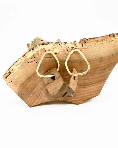 Wooden earrings on a natural wooden block with a white background