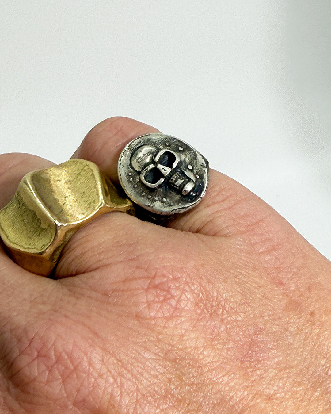 Gold and silver ring on a person's finger with a plain background