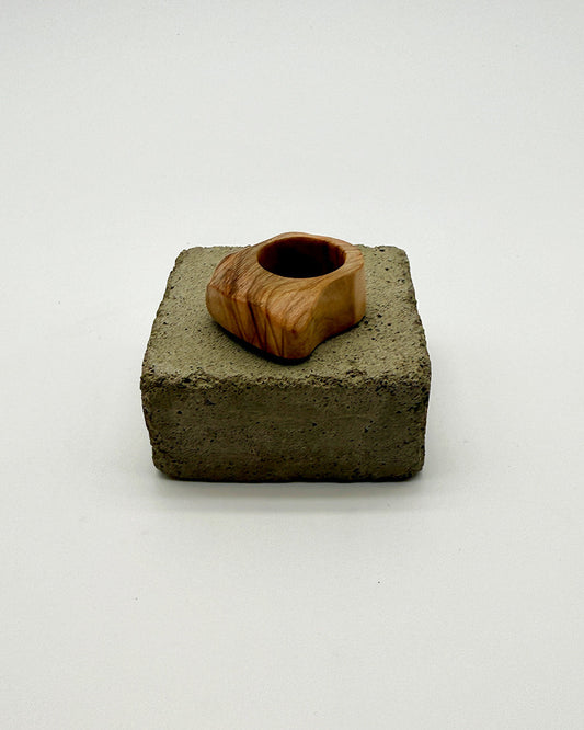 Wooden ring on a square concrete base against a white background