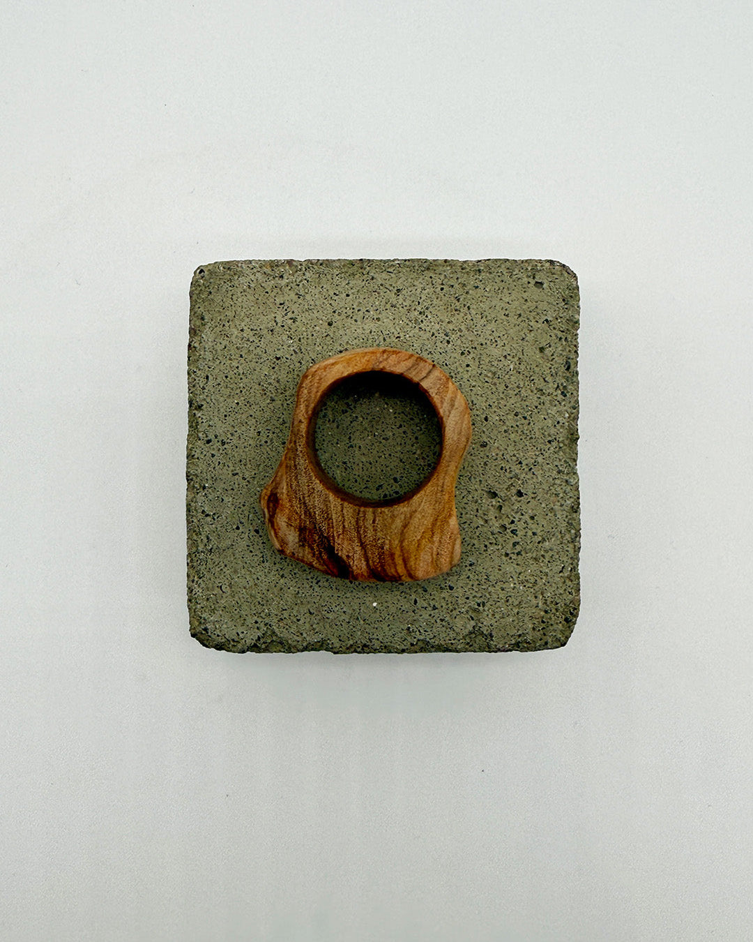 Square concrete coaster with a wooden ring on a white background