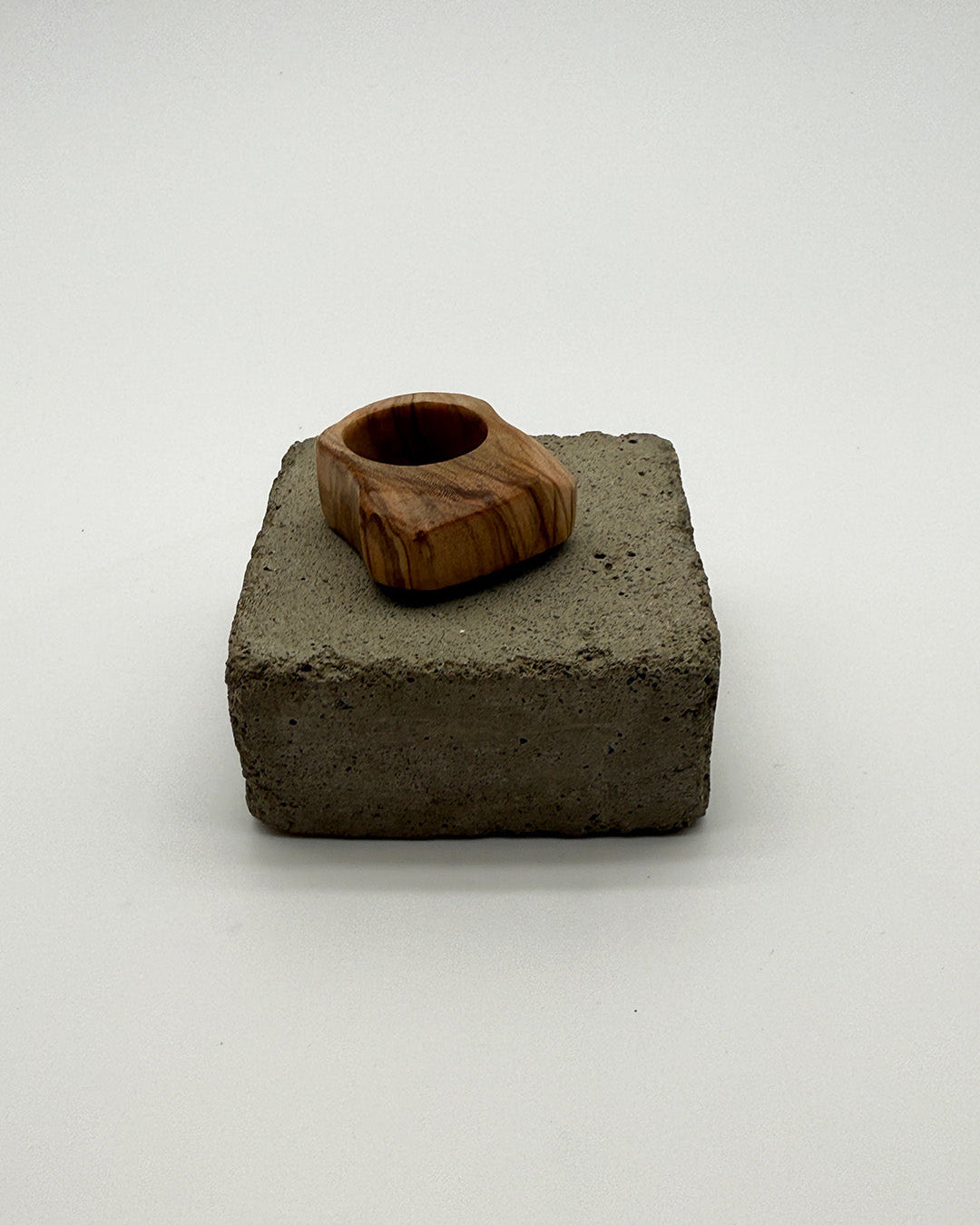 Wooden ring on a square concrete block against a white background