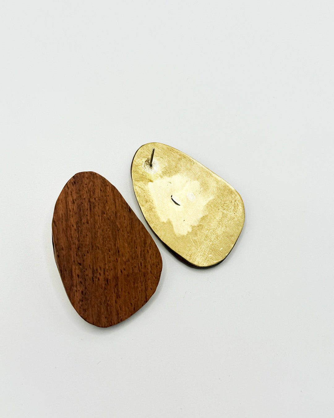 Gold and wooden earrings on a light gray background