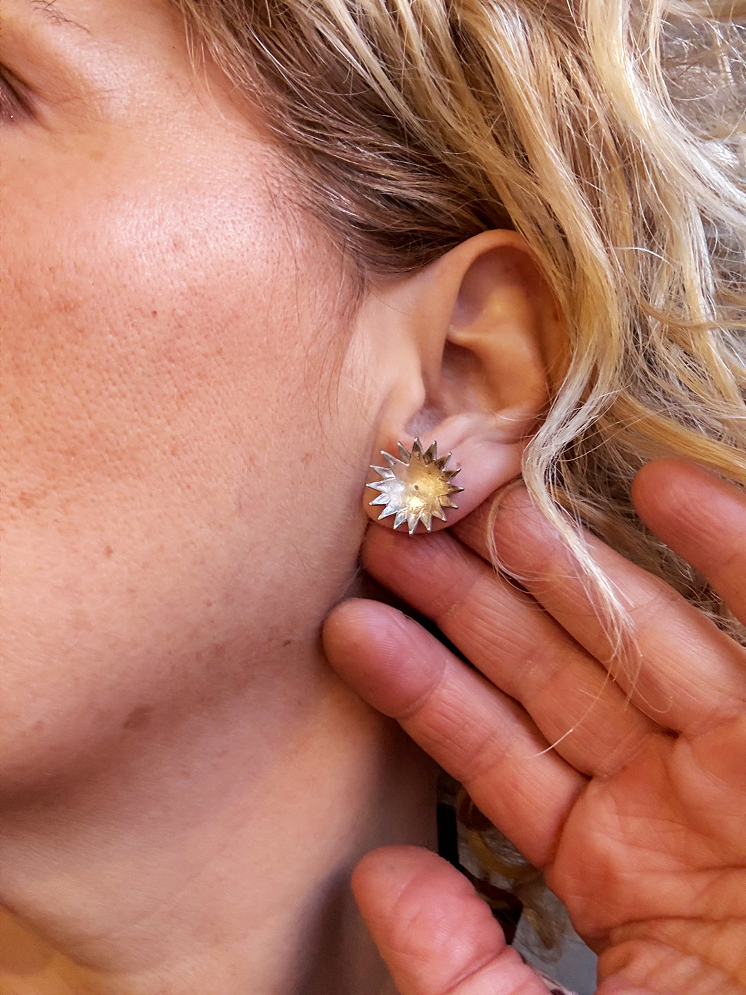 Close-up of a person wearing a floral earring with a blurred background