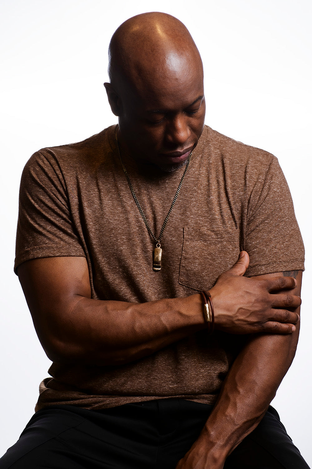 Man wearing a brown shirt with arms crossed on a white background