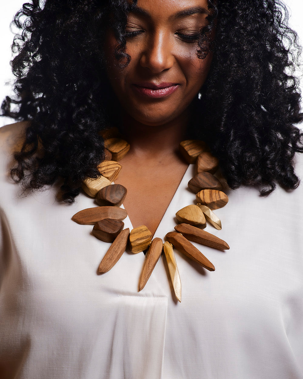 Woman wearing a large wooden necklace against a white background