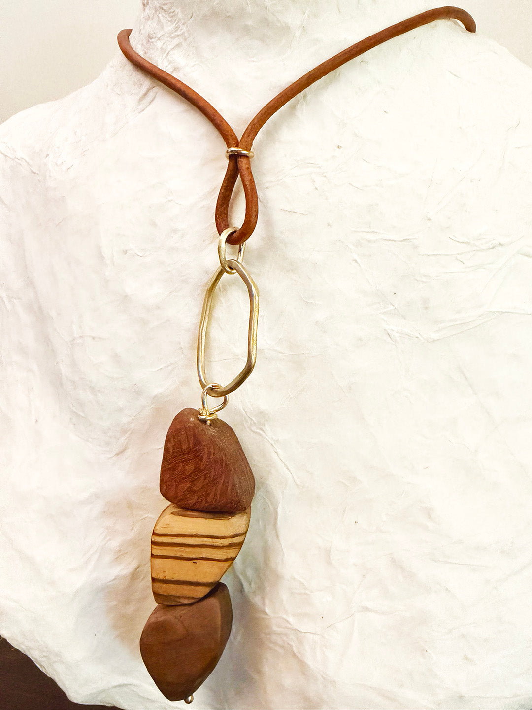 Necklace with wooden pendant and brown leather cord on a white background