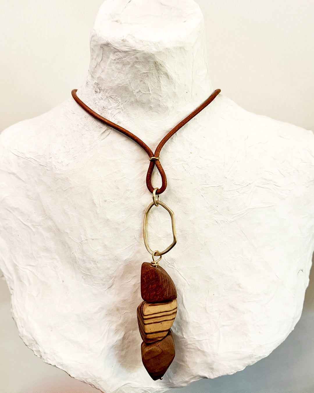Necklace with a wooden pendant on a mannequin bust against a white background