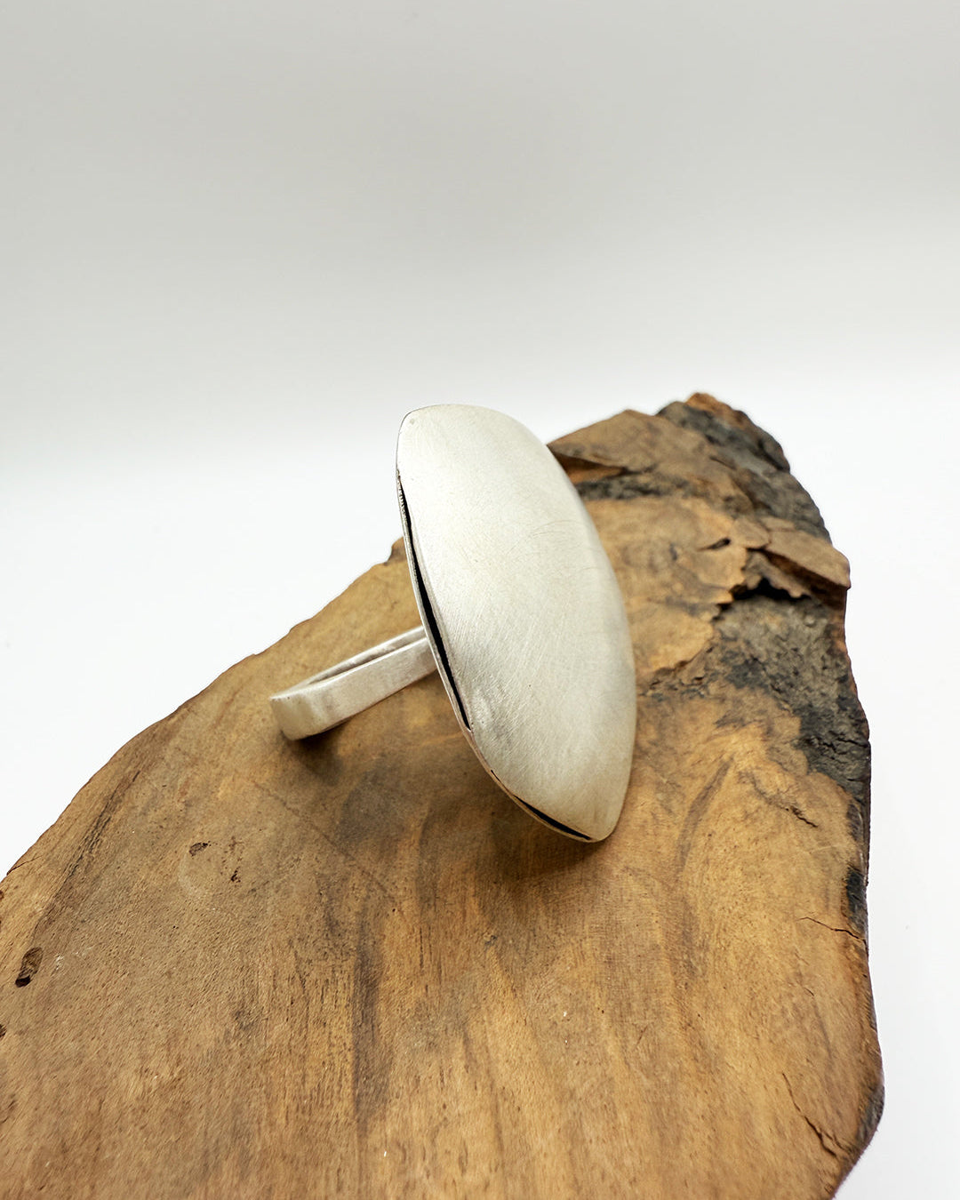 Silver ring on a wooden surface with a white background