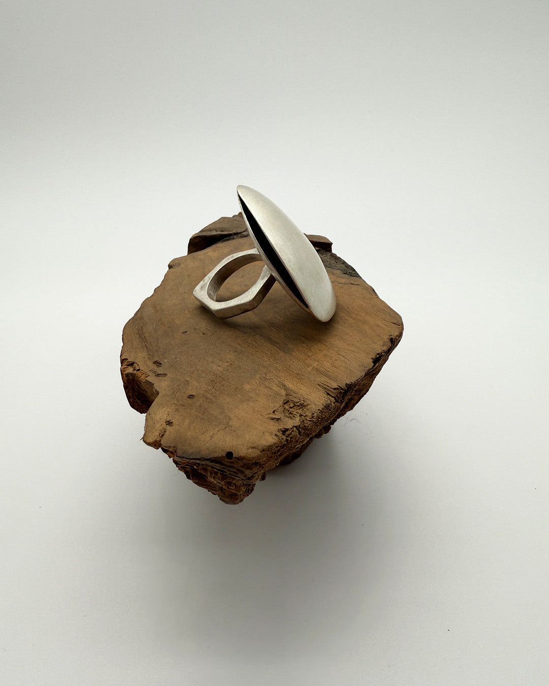 Silver ring on a piece of wood with a white background