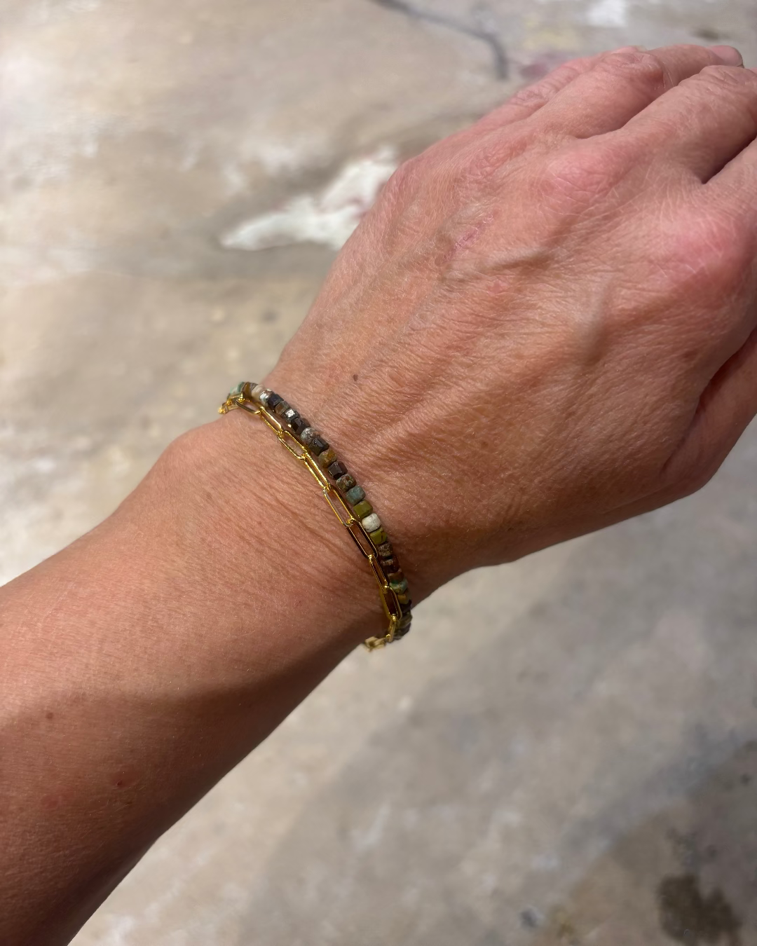 Hand wearing a beaded bracelet with a blurred natural background